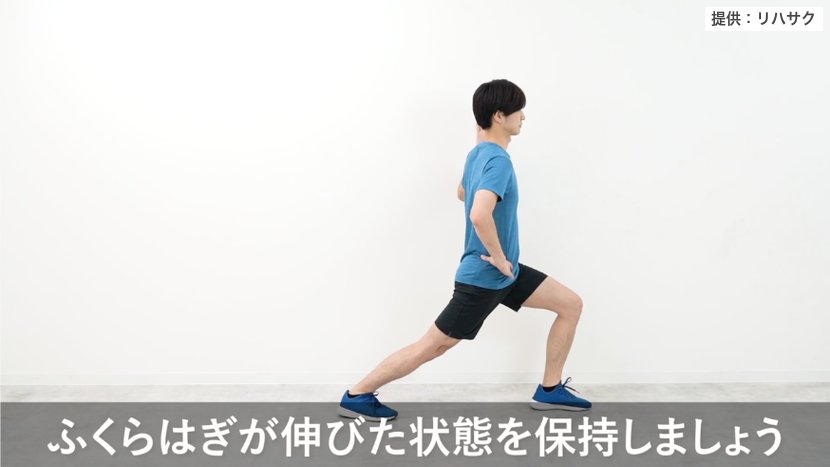 ふくらはぎのストレッチ:脚を前後に開き、後ろ脚の膝を伸ばしてかかとを床につけたまま体重を前へ