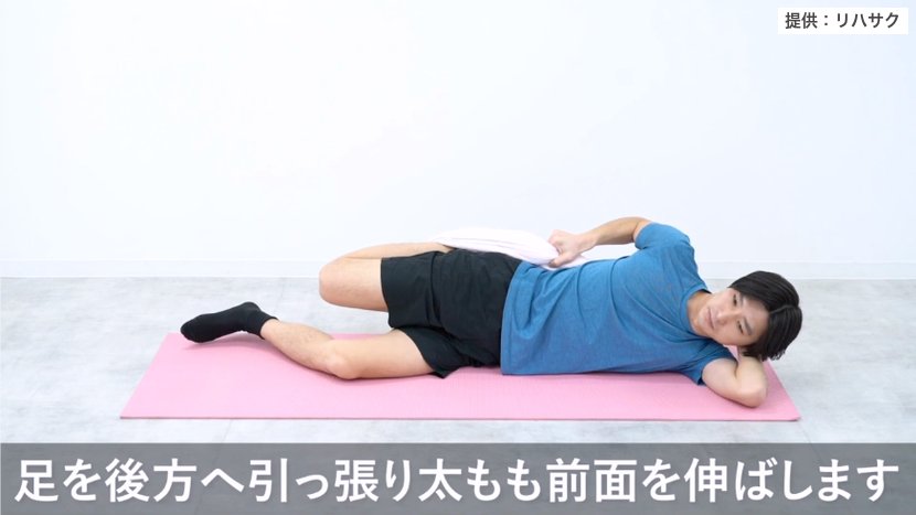 横向きに寝て足首にかけたタオルを後ろへ引き、太ももの前を伸ばすストレッチ