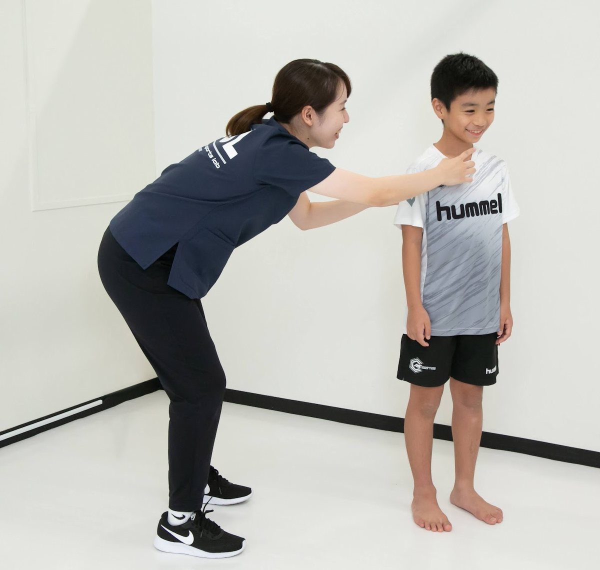 スタッフが小学生の立ち姿勢を確かめている様子（セミトレ）